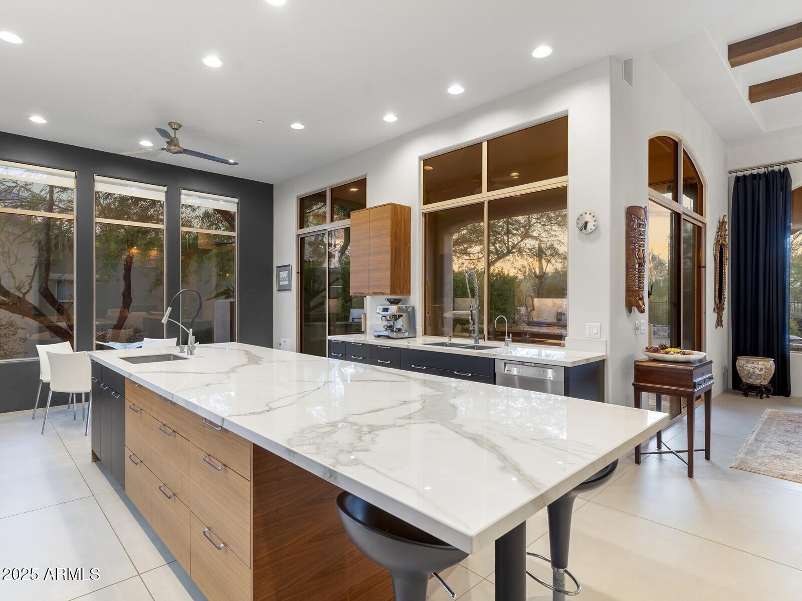 9290 East Thompson Peak Parkway, Unit 142 Scottsdale, AZ 85255 - Photo 19 of 74 a large kitchen with kitchen island a sink a stove a dining table and a large window with the wooden floor