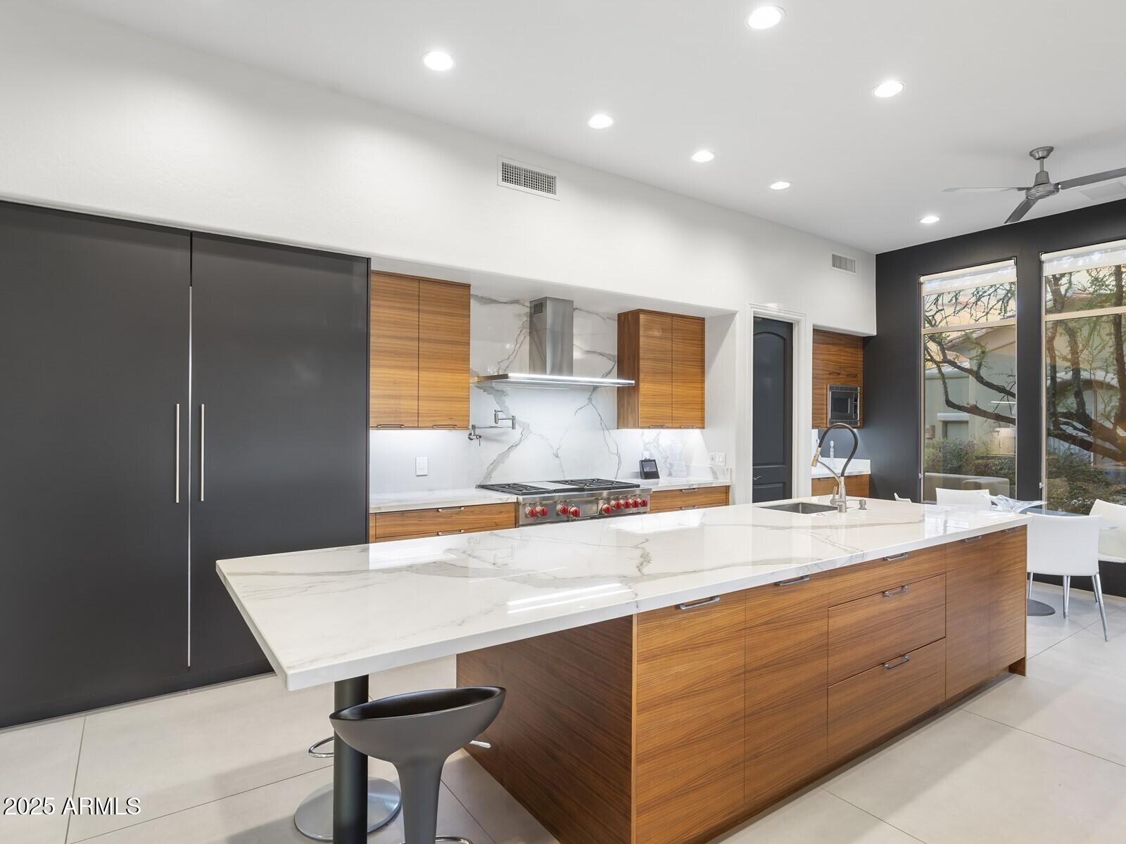 9290 East Thompson Peak Parkway, Unit 142 Scottsdale, AZ 85255 - Photo 21 of 74 a large kitchen with kitchen island a large counter top space a sink stainless steel appliances and cabinets