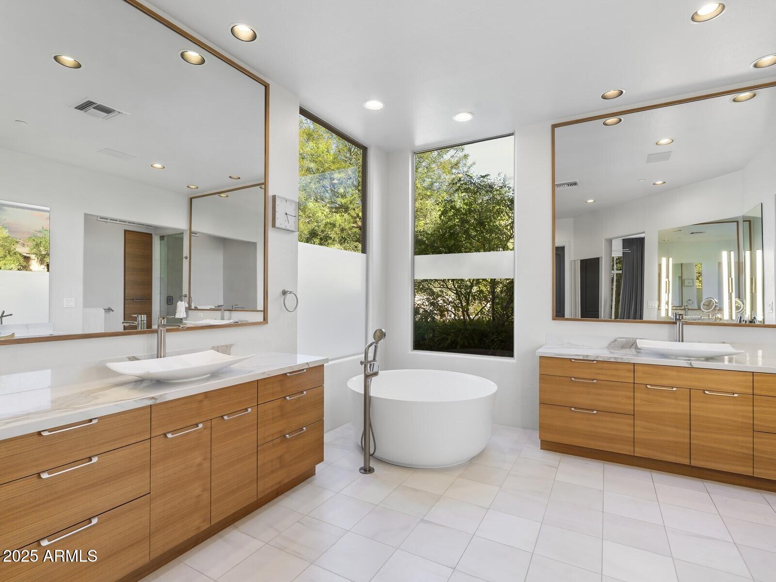 9290 East Thompson Peak Parkway, Unit 142 Scottsdale, AZ 85255 - Photo 31 of 74 a spacious bathroom with a double vanity sink a large mirror and a bathtub