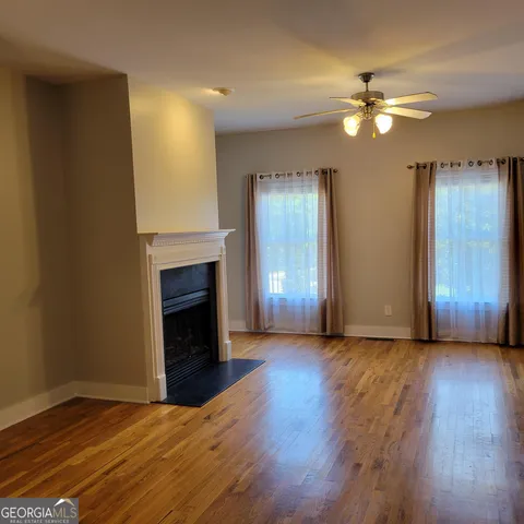 a view of an empty room with wooden floor and a fireplace