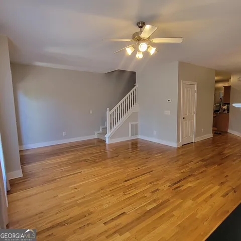 a view of an empty room with wooden floor and a chandelier