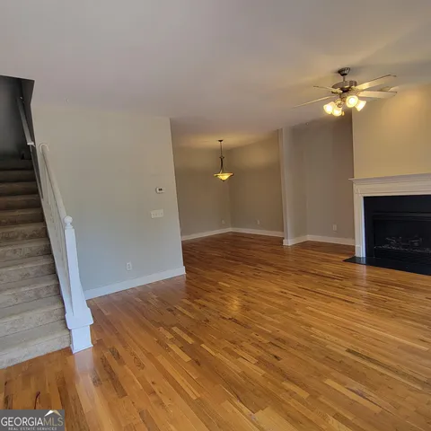 a view of an empty room with wooden floor and a fireplace