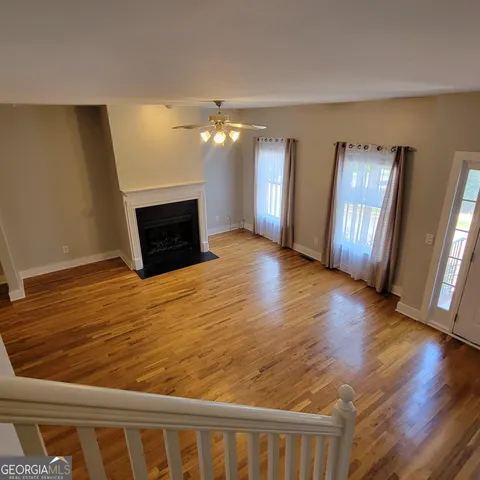 a view of an empty room with window and wooden floor