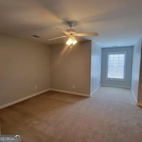 an empty room with windows and fan