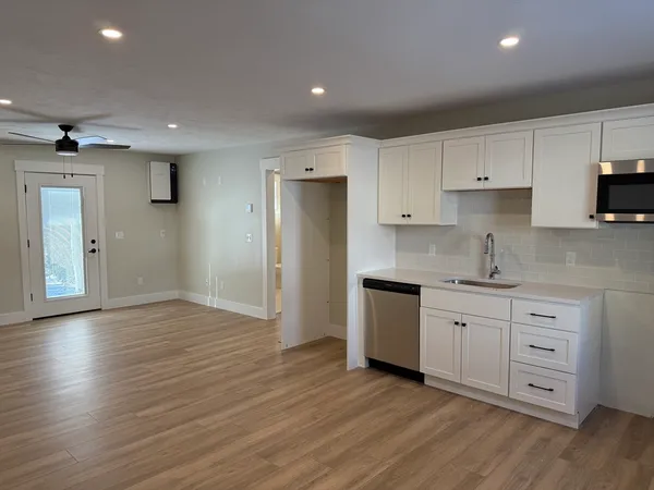 a kitchen with granite countertop a sink cabinets and wooden floor