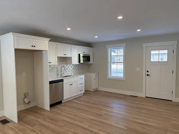 a large kitchen with stainless steel appliances granite countertop a stove a sink and white cabinets