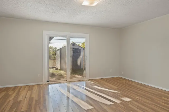 a view of an empty room with wooden floor and closet