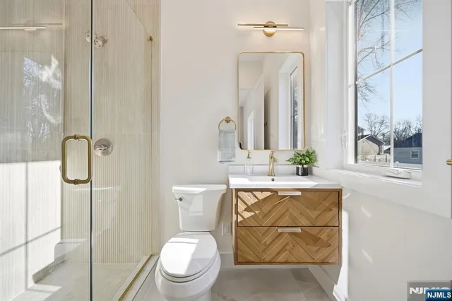 a bathroom with a granite countertop sink a toilet a mirror and shower