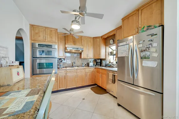 a kitchen with stainless steel appliances granite countertop a refrigerator a oven a sink and a refrigerator with wooden floor