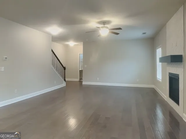 a view of an empty room with wooden floor fireplace and a window