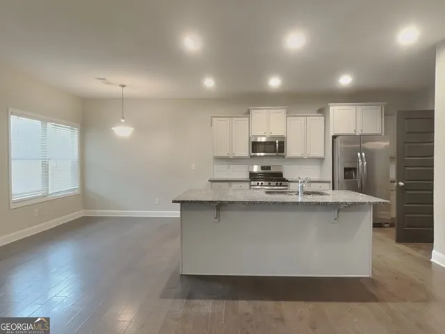 a kitchen with stainless steel appliances granite countertop a sink a stove a refrigerator cabinets and wooden floor