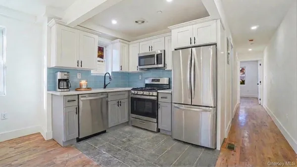 a kitchen with white cabinets stainless steel appliances and a refrigerator