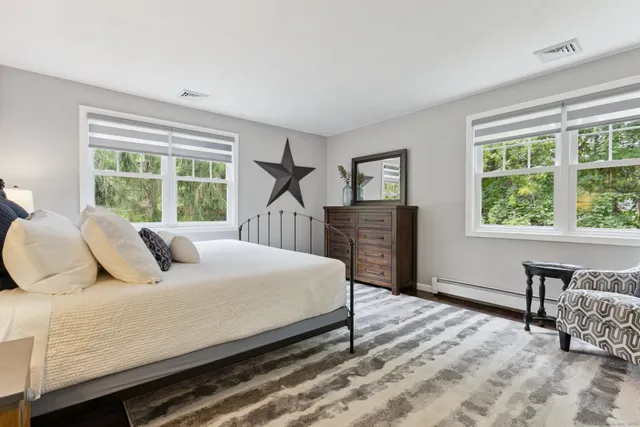 a bedroom with a bed and a dresser next to a window