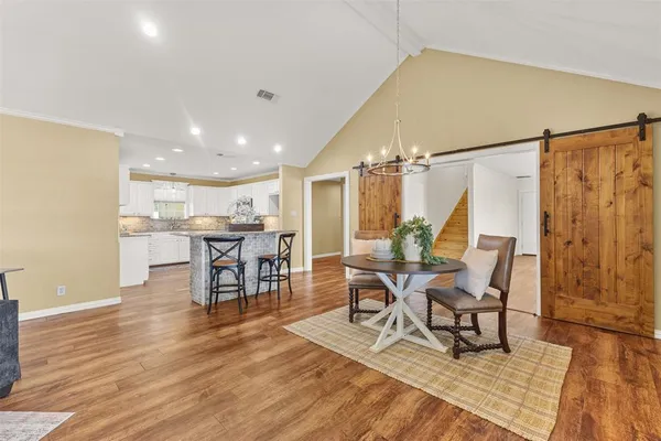 a dining room with stainless steel appliances kitchen island granite countertop a dining table chairs and a refrigerator