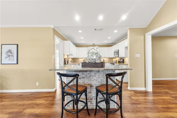 a kitchen with stainless steel appliances granite countertop a kitchen island a stove a cabinets a dining table and chairs