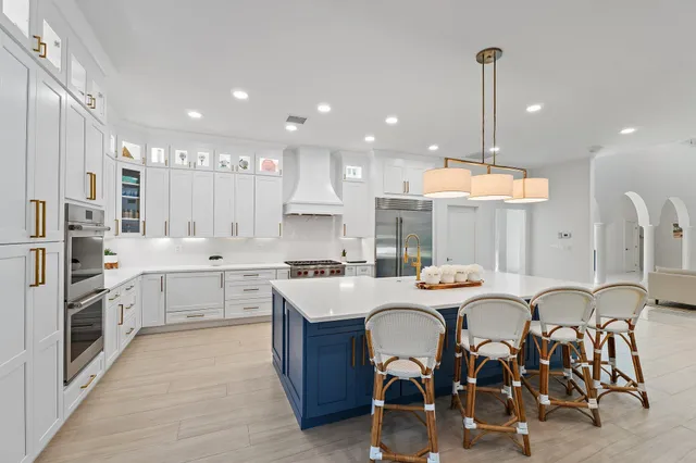 a room with stainless steel appliances kitchen island granite countertop a table chairs and a wooden floors