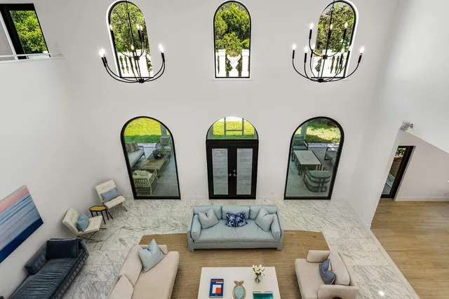 a living room with couches a mirror with wooden floor and windows