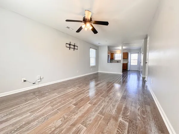 an empty room with wooden floor ceiling fan and windows