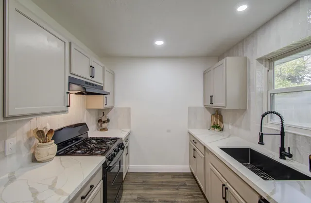 a kitchen with stainless steel appliances granite countertop a sink stove and cabinets