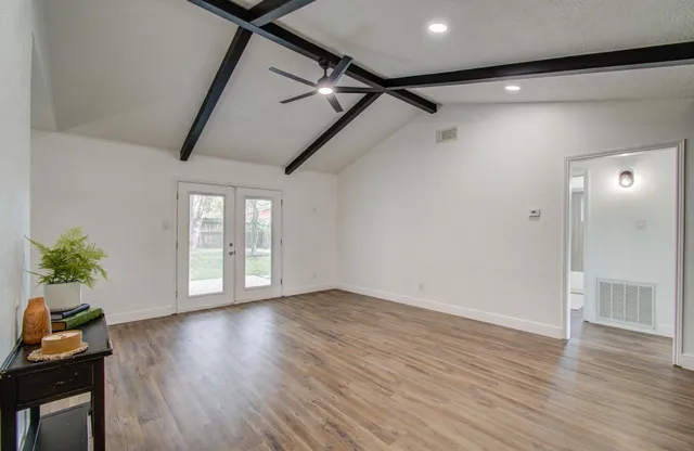 a view of an empty room with wooden floor and a window