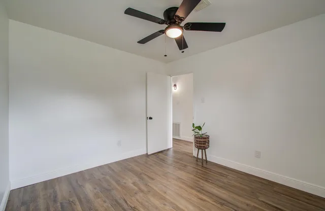 a view of room with wooden floor and a ceiling fan