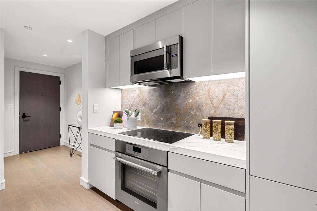 55 Lagrange Street, Unit 1901 Boston, MA 02111 - Photo 8 of 34 a kitchen with stainless steel appliances granite countertop a sink and a microwave