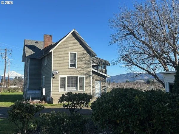 a front view of a house with a yard and mountain view in back