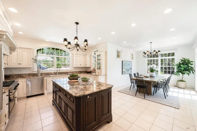 a kitchen with a stove top oven a sink dishwasher and a dining table with chairs