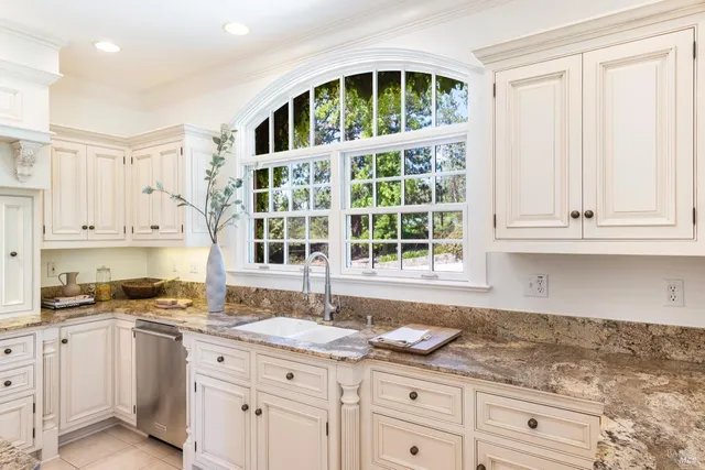 a kitchen with granite countertop white cabinets and window