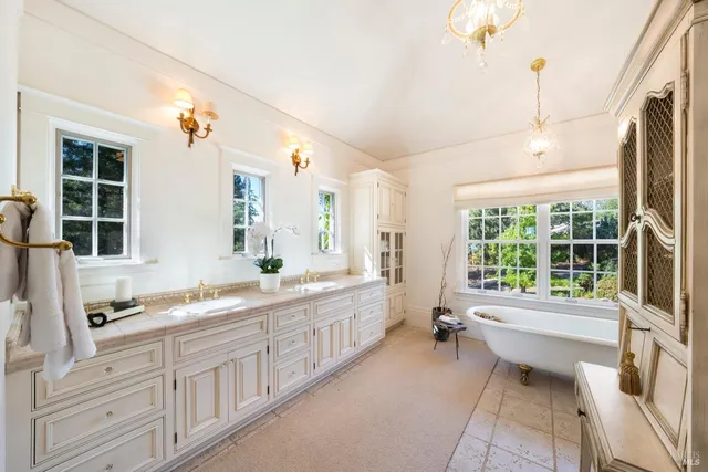a bathroom with a double vanity sink a large mirror and a bathtub next to a window