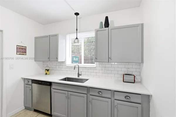 a kitchen with stainless steel appliances granite countertop a sink a window and white cabinets