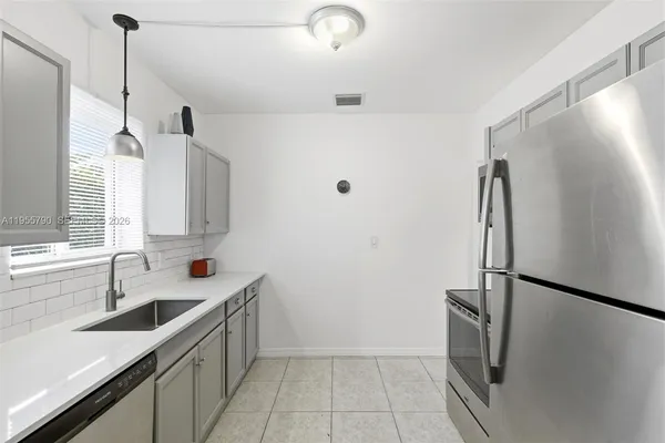 a kitchen with stainless steel appliances a sink a refrigerator a window and cabinets