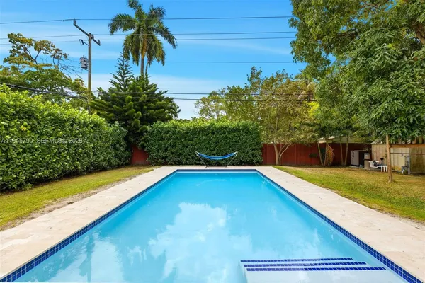 a view of a backyard with swimming pool and trees in the background