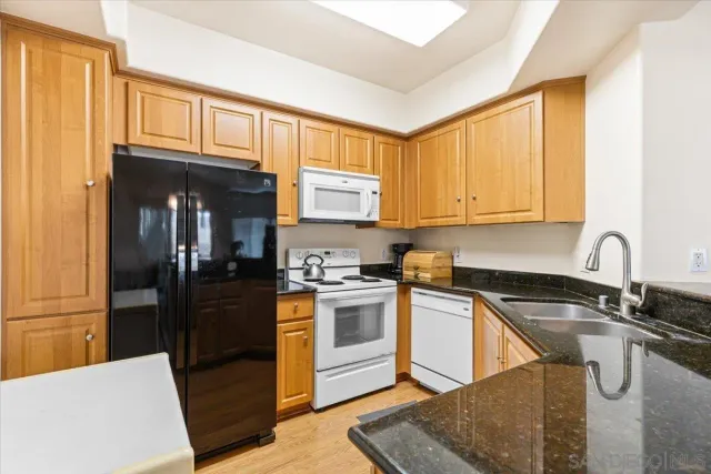 a kitchen with granite countertop a sink cabinets and stainless steel appliances
