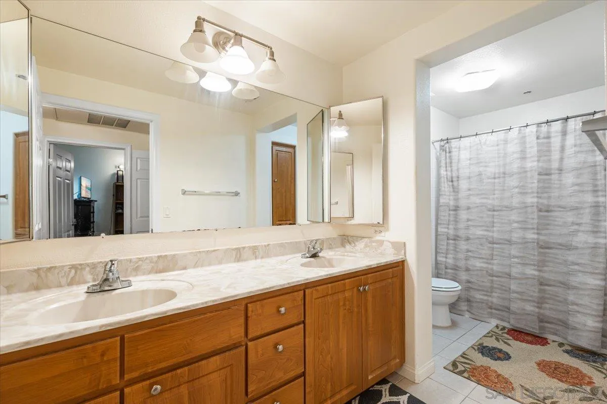 2715 Lake Pointe Drive, Unit 116 Spring Valley, CA 91977 - Photo 8 of 25 a bathroom with double vanity sink a mirror and a toilet