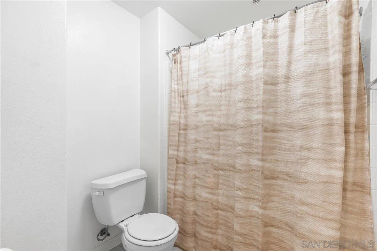 2715 Lake Pointe Drive, Unit 116 Spring Valley, CA 91977 - Photo 9 of 25 a white toilet sitting next to a shower curtain