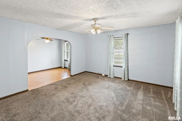 an empty room with chandelier fan and windows