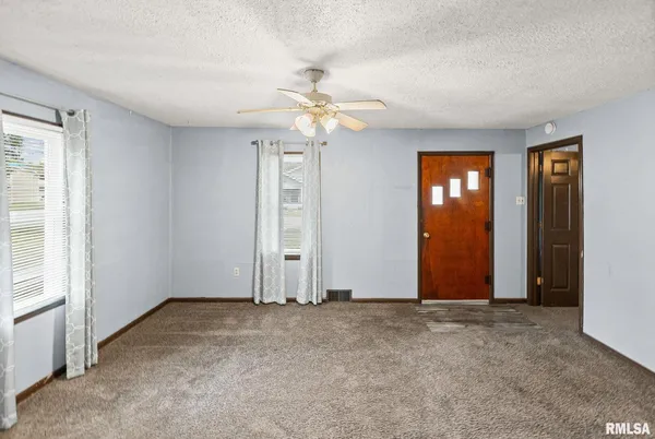 an empty room with windows and fan
