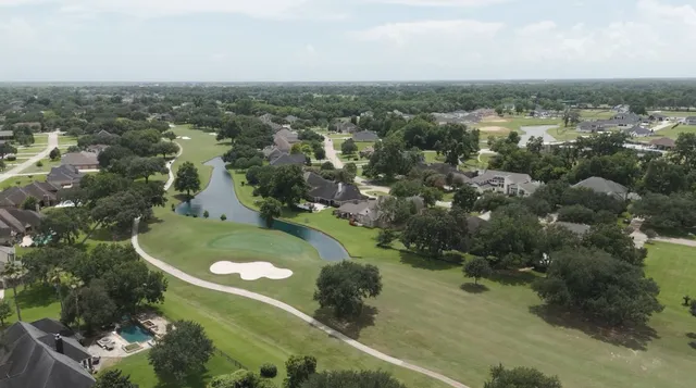 an aerial view of a residential houses with outdoor space and trees
