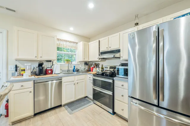 a kitchen with white cabinets stainless steel appliances and window