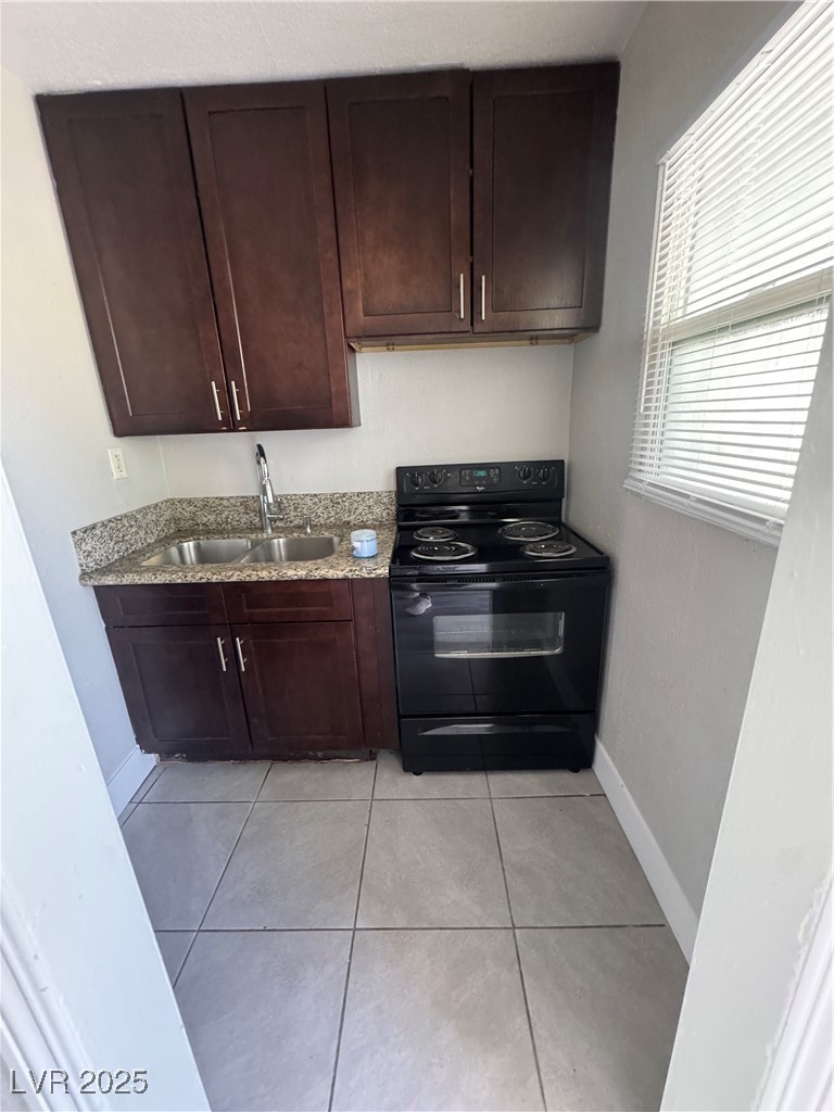 640 North 9th Street, Unit 3 Las Vegas, NV 89101 - Photo 9 of 11 Kitchen with black / electric stove, dark brown cabinetry, light tile patterned floors, and light stone counters