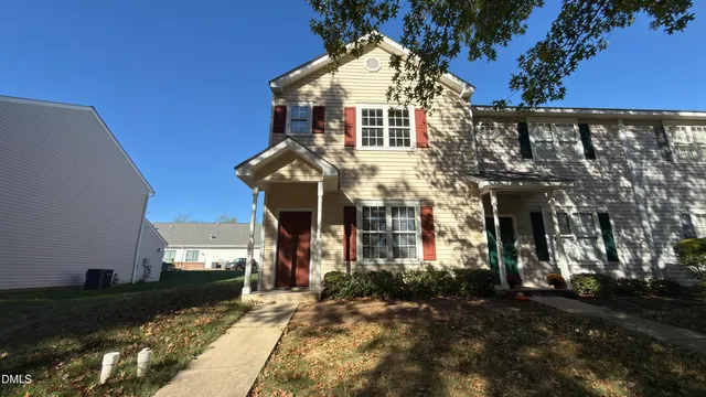 a view of a white building among the street with plants and trees