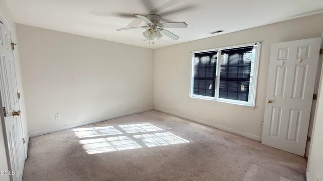 an empty room with windows and fan