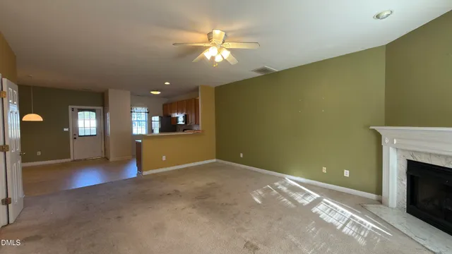 an empty room with a fireplace and chandelier fan