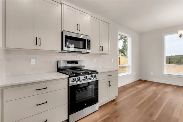a kitchen with stainless steel appliances white cabinets and a stove top oven
