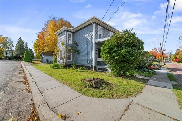 a view of a house with a small yard and a large tree