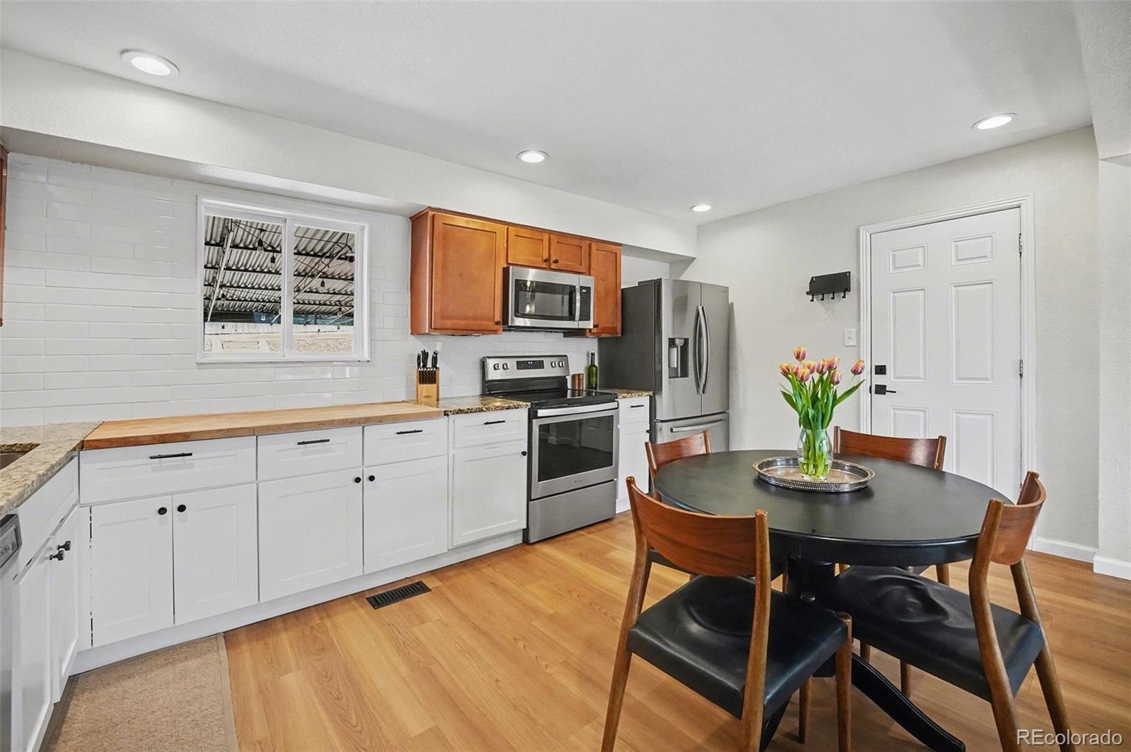 8207 High Street Denver, CO 80229 - Photo 9 of 31 a kitchen with stainless steel appliances granite countertop a stove a sink a microwave a dining table and chairs