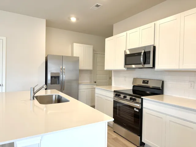 a kitchen with kitchen island a sink stainless steel appliances and cabinets