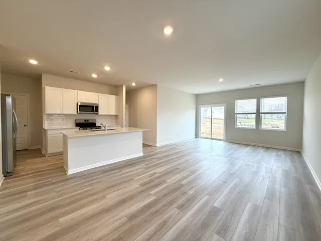 a view of kitchen with kitchen island wooden floors and stainless steel appliances