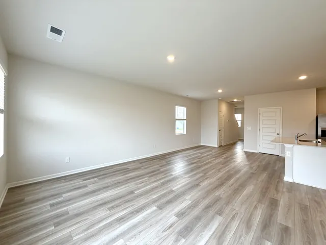 a view of empty room with wooden floor and window